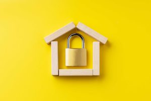 Fundo amarelo com casa de madeira e cadeado dentro