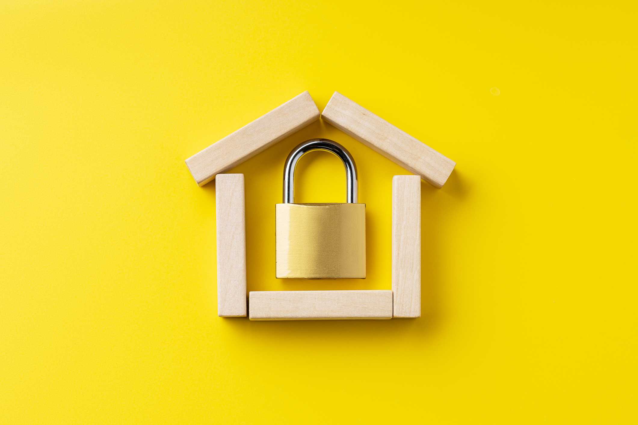 Fundo amarelo com casa de madeira e cadeado dentro